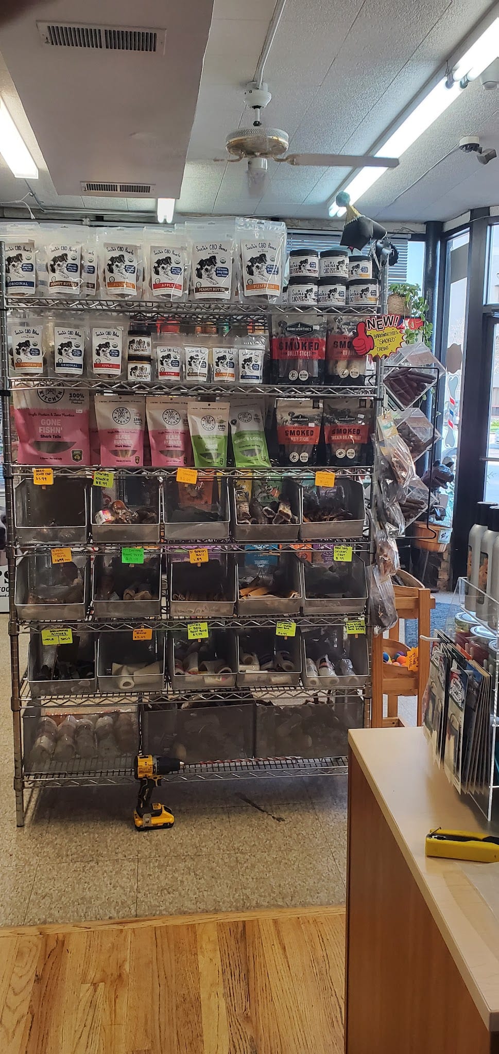 Metal shelving unit stocked with dog treats, bones, and CBD products