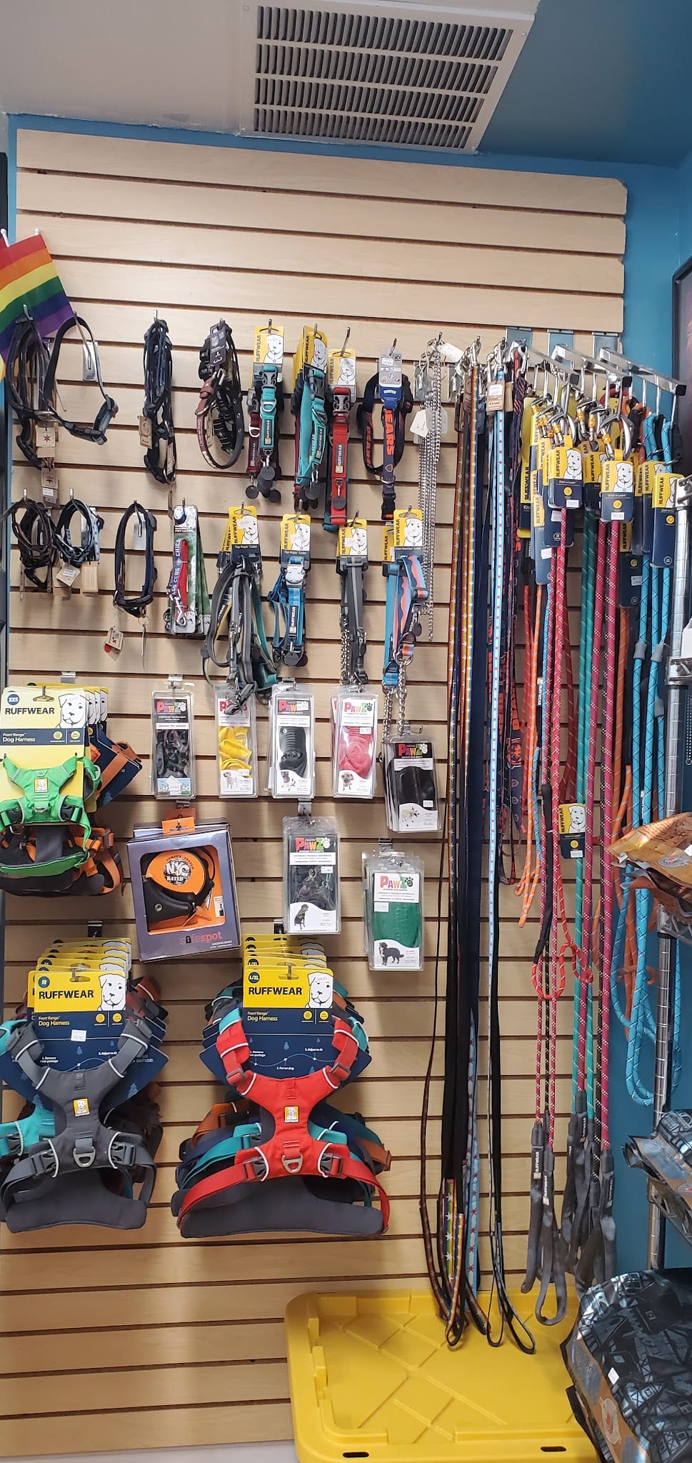 Wall display of dog collars, leashes, and Ruffwear harnesses in pet store