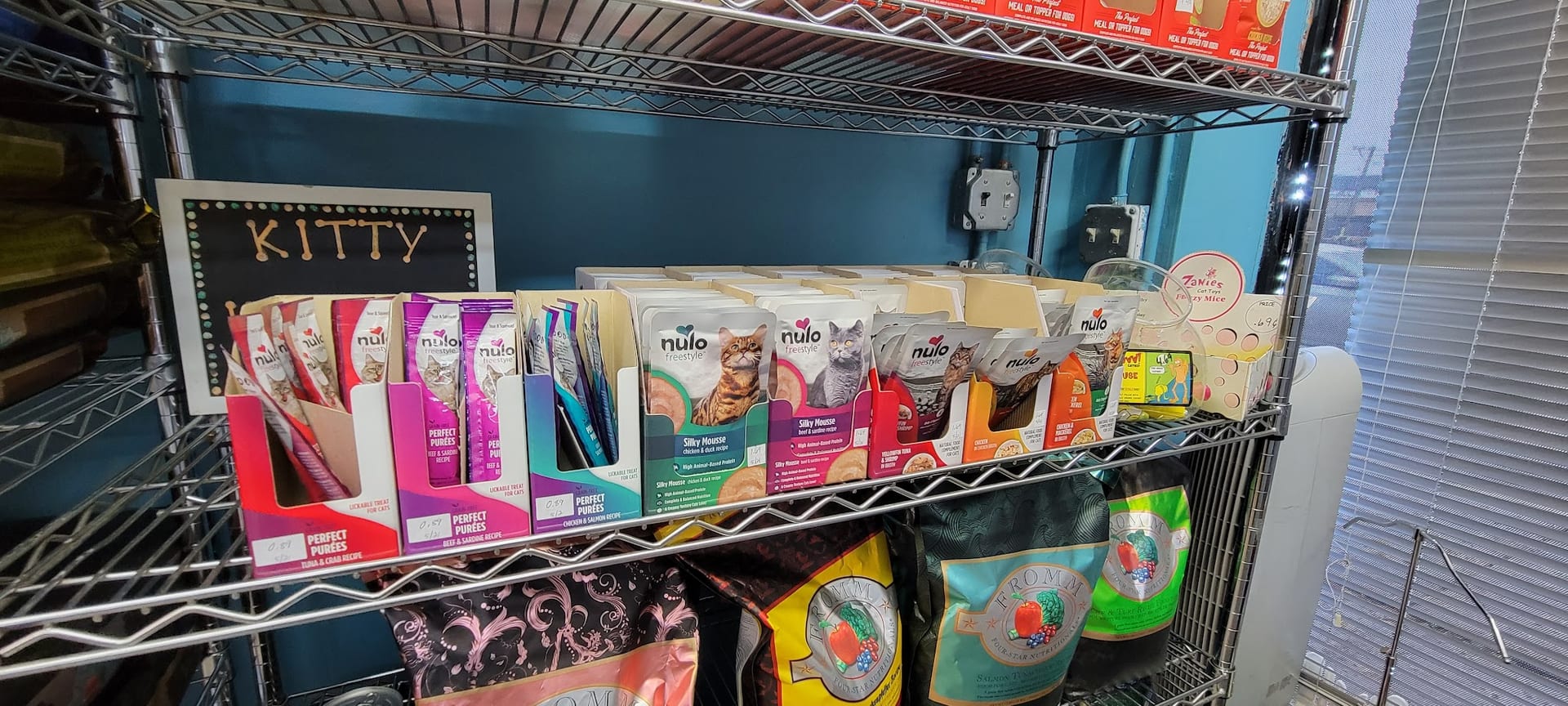 Wire shelf stocked with Nulo Freestyle cat food pouches and Fromm dry food bags